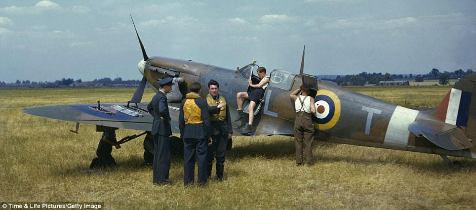 Pilots chatting, as the aircrew work on their Spitfire